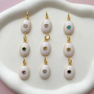 Golden oval pendants with colorful gemstones and white enamel on a display tray