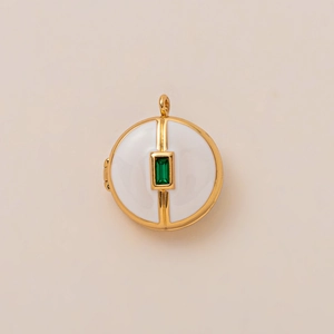 Detailed view of an 18K gold-plated locket with white enamel and green gemstone inlay