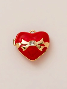 Macro detail of red enamel heart locket with golden bow and square zircon stone inlay