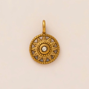Macro detail of sunburst pendant with center crystal and vintage gold plating texture