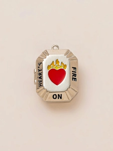 Locket detail showing silver metal locket with red enamel heart and fire engraving