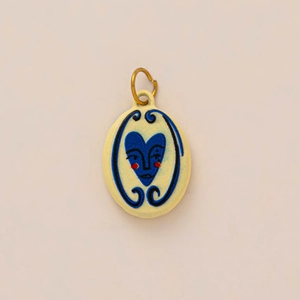 Macro detail of oval ceramic pendant featuring blue heart face design with gold ring