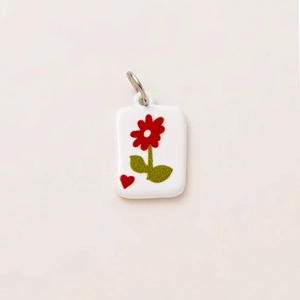 Detailed view of rectangular floral pendant with red flower and gold plating loop