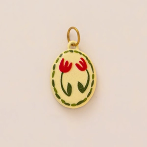 Detail of oval enamel tulip pendant with red flowers and green leaves on gold plating