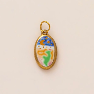 Macro detail of oval gold pendant with colorful enamel night sky and crescent moon design