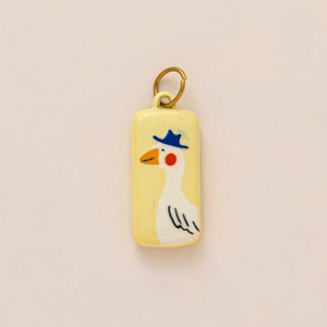 Detailed macro view of a rectangular yellow pendant with a cute cartoon goose illustration