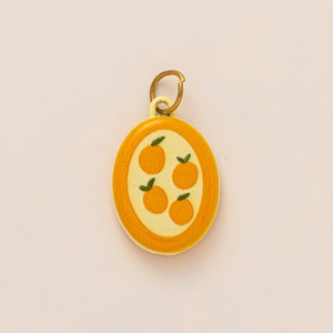 Detail of a 18k gold plated stainless steel round pendant with orange fruit pattern