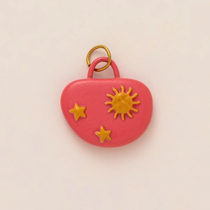 Pink heart pendant with gold sun and star embossing on a clean cream background