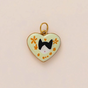Detail of heart-shaped green enamel pendant with cat and floral motifs in gold finish
