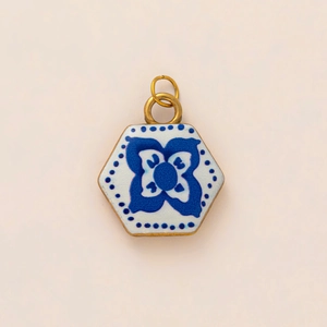 Macro detail of hexagonal ceramic pendant featuring vintage blue floral patterns and gold loop