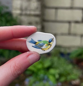Vue détaillée d'un pendentif ovale en céramique avec motif d'oiseau peint à la main