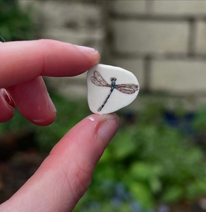Vue macro d'un petit pendentif en pierre blanche orné d'un imprimé libellule
