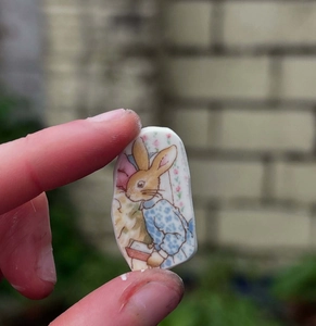Gros plan d'un pendentif en porcelaine avec un lapin de conte classique en veste bleue