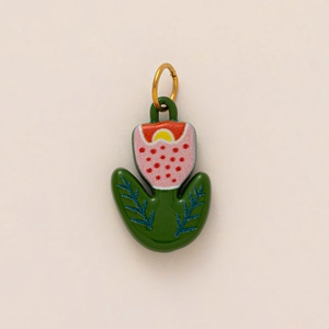 Detailed macro of a green floral pendant with pink flowers and a gold hanging ring