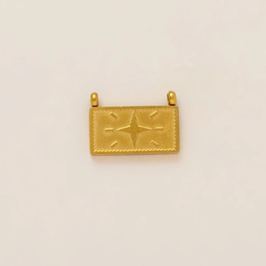 Macro detail of a 18K gold plated rectangular charm with a compass star engraving