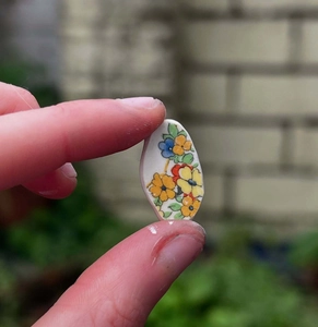 Gros plan détaillé d'un pendentif ovale en céramique peint à la main avec fleurs