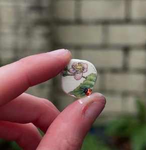 Détail macro d'un pendentif en céramique artisanale avec coccinelle et motif floral