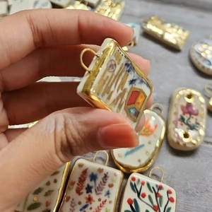 Macro shot of colorful hand-painted ceramic pendant charms with gold-plated metal edges