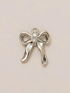 Close-up of silver bow pendant with cubic zirconia stones and metal ring connector