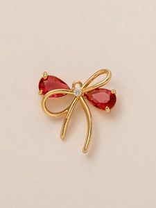 Close-up of golden bow pendant with two red pear-cut stones and center crystal detail