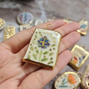 Macro shot of a floral printed rectangular pendant with 18K gold plated metal borders
