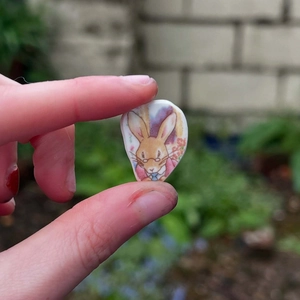 Mini pendentif lapin vintage avec lunettes tenu entre les doigts en décor extérieur