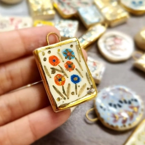 Detailed close-up of 18K gold plated flower pendant with hand-painted ceramic inlay