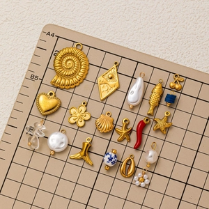 Variety set of 18K gold plated marine charms and pendants on a grid measurement mat