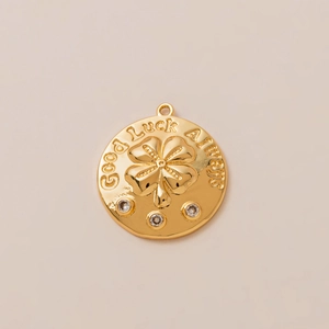 Macro detail of round 18K gold plated clover pendant with Good Luck Always engraving