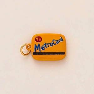 Gros plan d'un porte-clés MetroCard jaune avec lettrage bleu et anneau doré