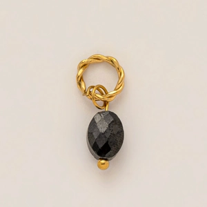 Détail macro d'un pendentif anneau torsadé plaqué or 18K avec une pierre noire facettée