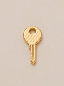 Detail of 18K gold plated key pendant featuring a micro-grid textured round head and stem