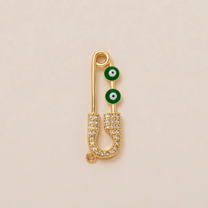 Macro shot of gold-plated safety pin pendant with green evil eye and white zircon stones