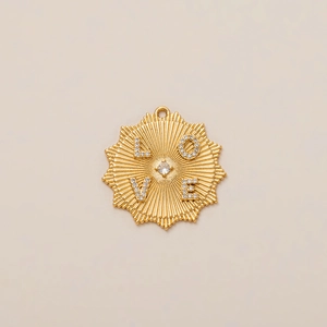 Macro shot of gold sunburst pendant with LOVE inscription and centered cubic zirconia