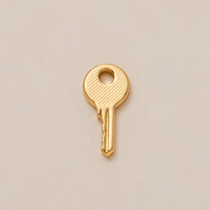 Polished 18K gold-plated copper key charm with textured head and smooth metallic finish