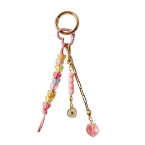 DIY gold keychain with peach charm, heart beads, and sun pendant on white background