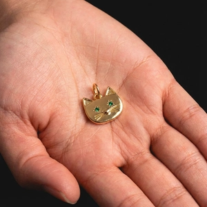 14K gold plated cat pendant with green zircon eyes shown on hand for size reference