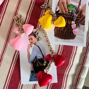 Three colorful resin heart bag charms in pink, yellow, and red with gold metal lobster clasps