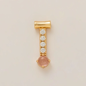 Detalle de colgante chapado en oro con cuatro circonitas y una piedra rosa