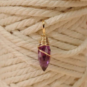 Détail d'un pendentif en pierre violette facettée avec enroulement en fil d'or 14K