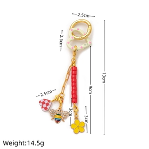 Détail des breloques émaillées abeille et cœur sur un porte-clés doré 18K de 13 cm de long