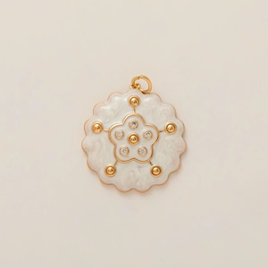Detalle de un colgante de flor bañado en oro con esmalte blanco y cristales brillantes