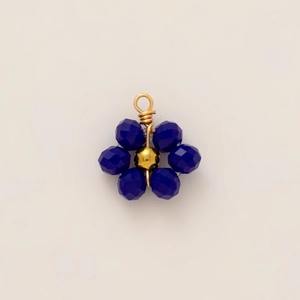 Macro detail of a 18k gold plated floral pendant with deep blue faceted beads