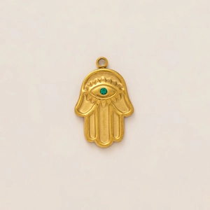 Detail view of a 18K gold Hamsa pendant with an engraved eye and a green zircon stone