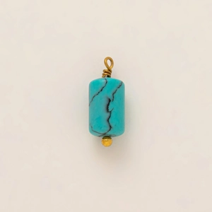 Macro view of a cylindrical turquoise pendant with gold-plated wire-wrapped ring detail