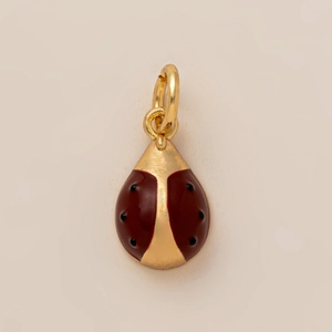 Détail d'un pendentif coccinelle doré avec émail rouge et taches noires