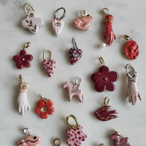 Colorful enamel heart, bird and frog pendants on marble background for jewelry making
