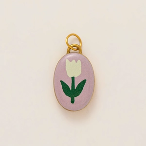 Gros plan d'un pendentif ovale doré avec paillettes violettes et motif floral de tulipe blanche