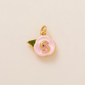 Détail d'un pendentif rose en émail avec des accents dorés et une petite feuille verte