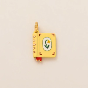 Détail du pendentif livre jaune avec fermoir mousqueton doré et motif floral délicat